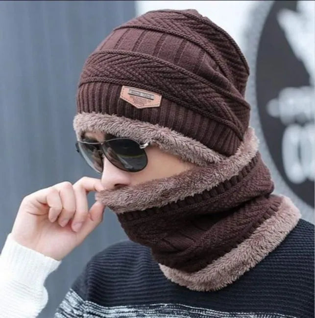 Person wearing a brown knitted hat and scarf set with sunglasses, against a blurred background.