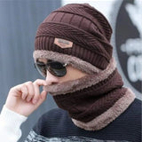 Person wearing a brown knitted hat and scarf set with sunglasses, against a blurred background.